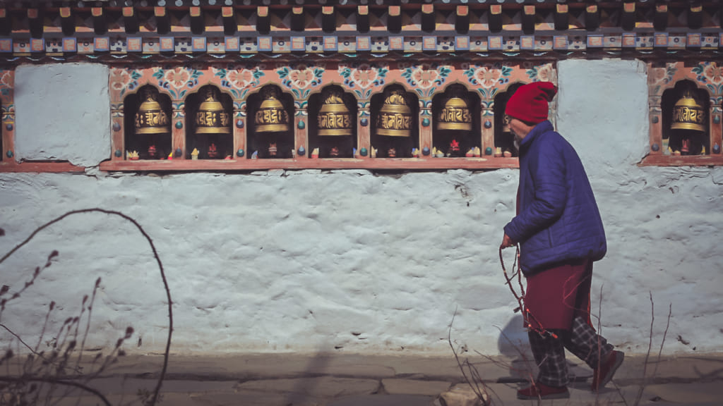 Cụ già bước qua các chuông bên ngoài ngôi đền Bhutan