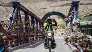 Du khách Fit Tour chạy xe mô tô qua cầu đầy cờ lungta