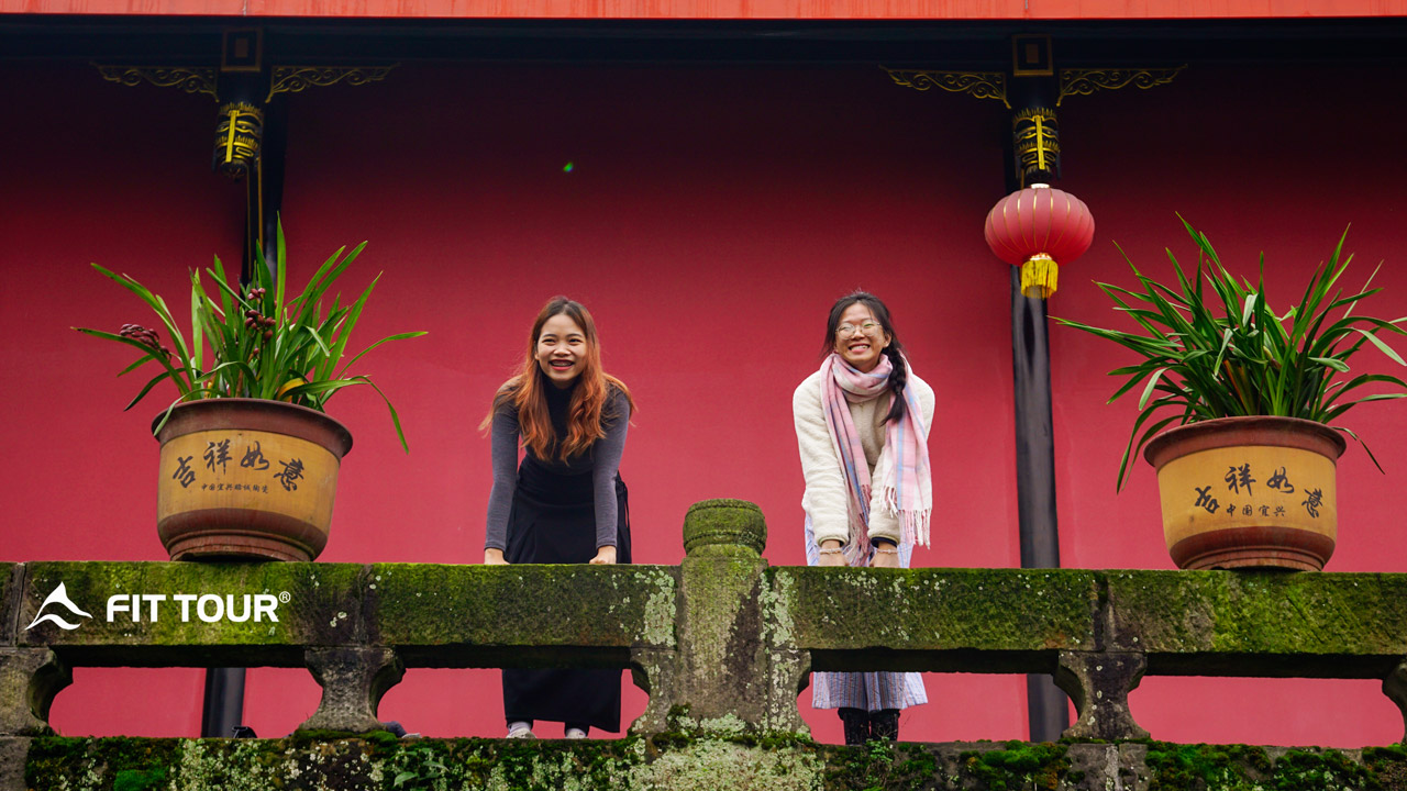 Hai du khách tươi cười check in trước ngôi chùa tại núi Nga Mi