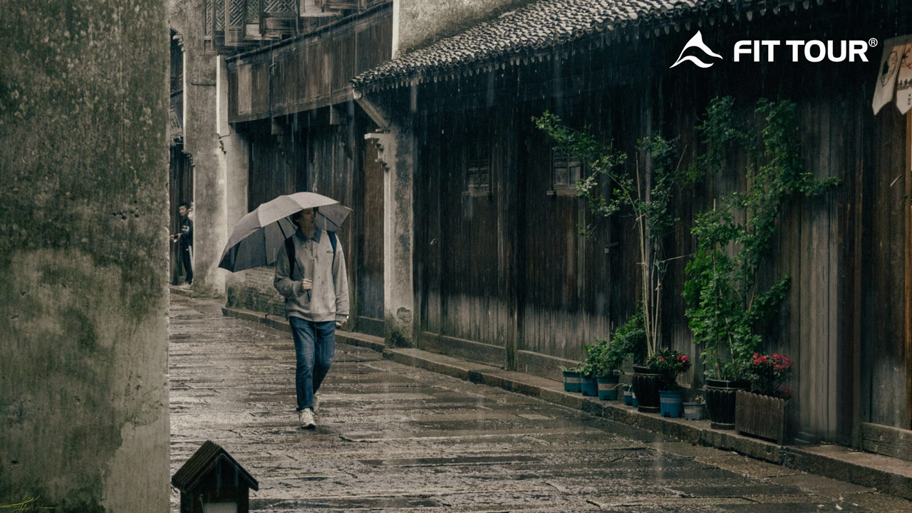 Du khách mang ô đi bộ giữa thời tiết mưa ở Ô Trấn