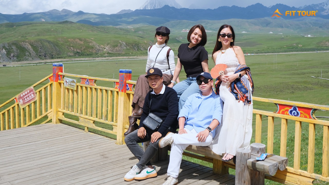 Nhóm du khách FIT TOUR chụp ảnh trên đài quan sát tại Tagong, phía sau là thảo nguyên và núi tuyết