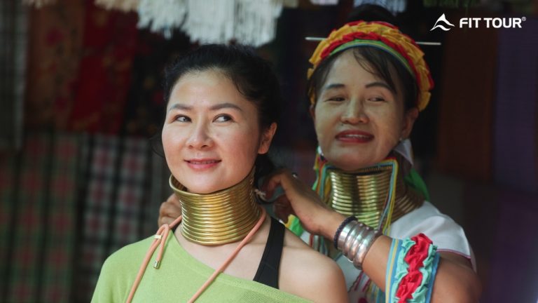 Người phụ nữ Karen cổ dài giúp du khách đeo vòng đồng truyền thống tại làng Long Neck Karen, Mae Hong Son, Thái Lan