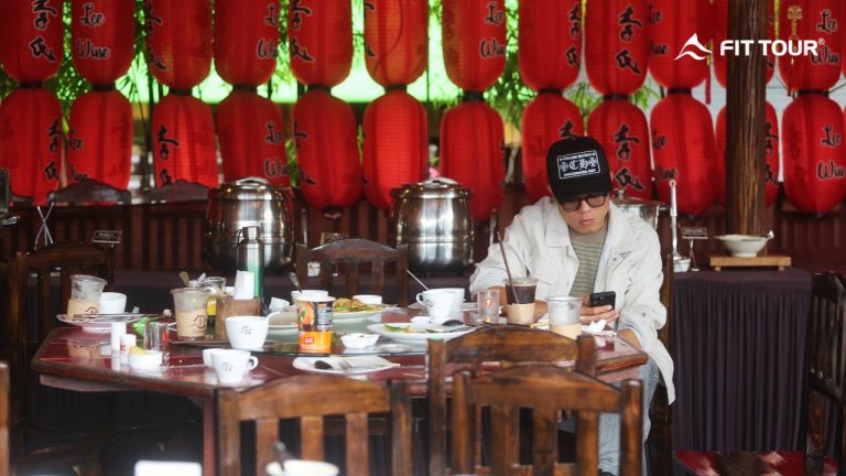 Khách du lịch ngồi tại quán cà phê trang trí đèn lồng đỏ, thưởng thức đồ uống và trò chuyện cùng bạn bè trong chuyến đi cùng FIT Tour
