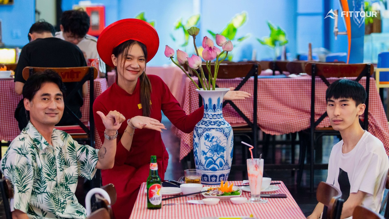 Du khách dùng bữa tối tại nhà hàng Bùi Viện, nhân viên mặc áo dài đỏ phục vụ trong không gian trang trí truyền thống