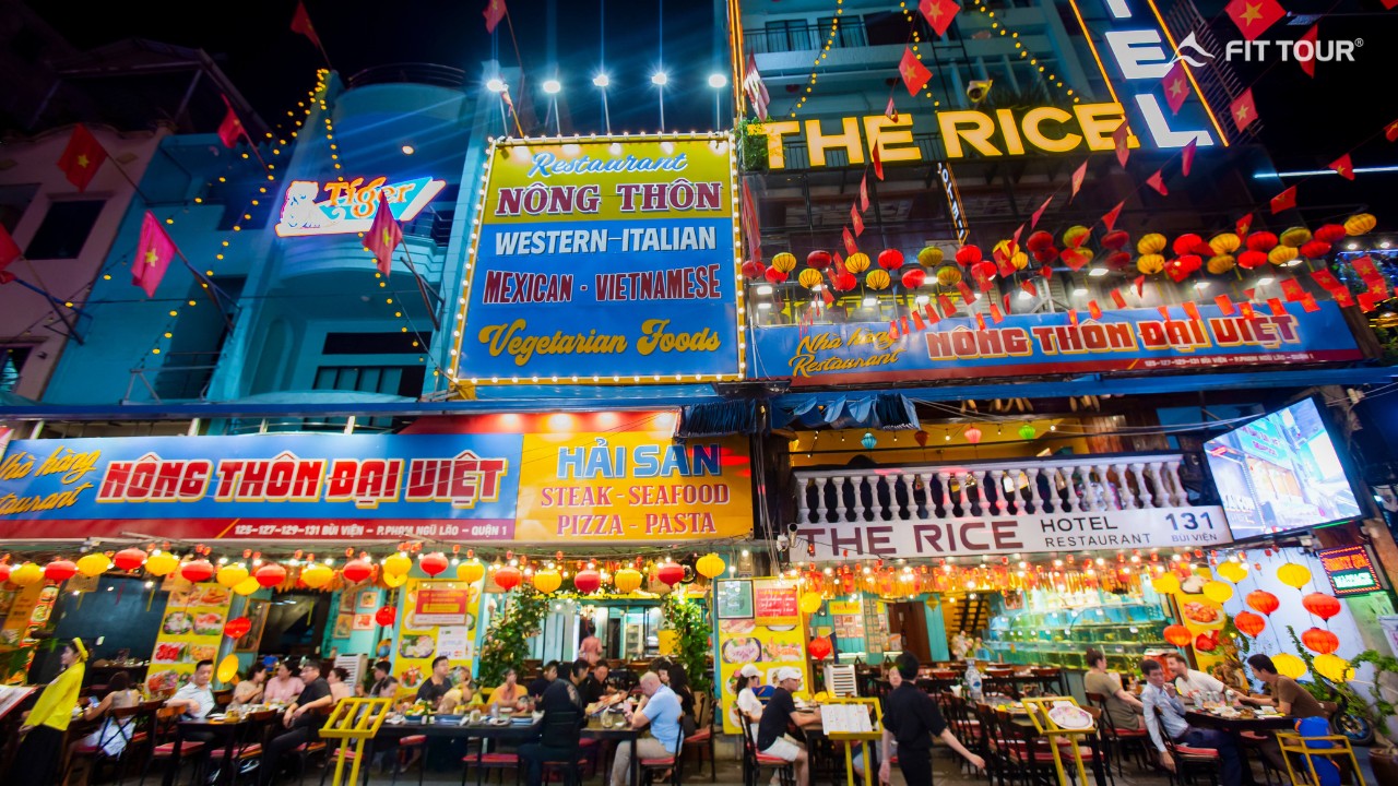Mặt tiền The Rice Hotel & Nhà hàng Nông Thôn Đại Việt trên phố Bùi Viện, nổi bật với biển hiệu rực sáng và hàng loạt lựa chọn ẩm thực quốc tế, hải sản và món Việt
