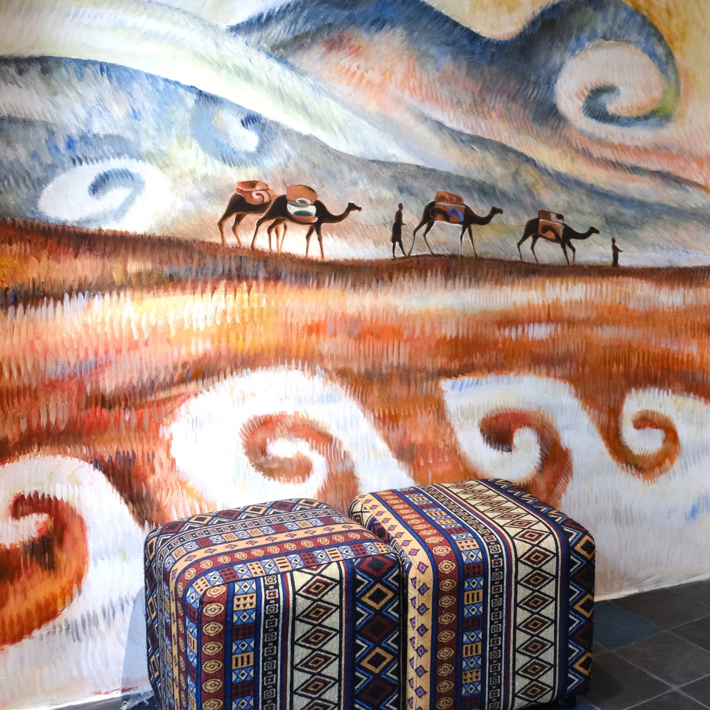 Silk Road art wall at FIT TOUR office – camel caravan painting evoking endless travel inspiration