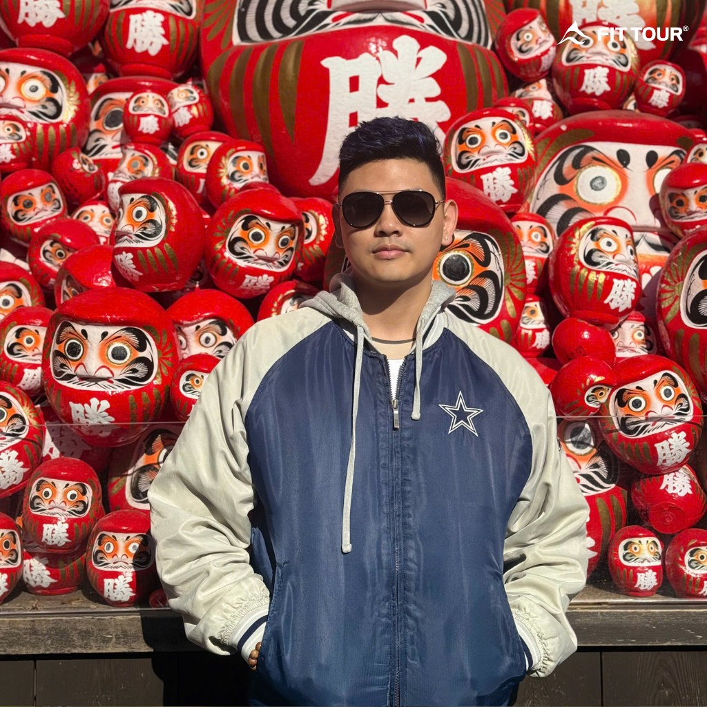 Khách hàng nam của FIT Tour check-in cực "ngầu" trước bức tường búp bê Daruma cầu may mắn.