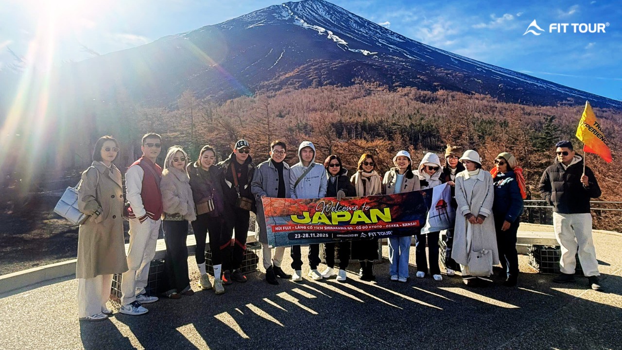 Đoàn khách FIT Tour chụp ảnh lưu niệm cùng băng rôn tại điểm ngắm núi Phú Sĩ hùng vĩ.