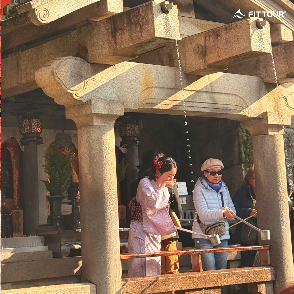 Du khách và người dân mặc Kimono thực hiện nghi thức rửa tay thanh tịnh (Temizuya) trước khi vào đền thờ.