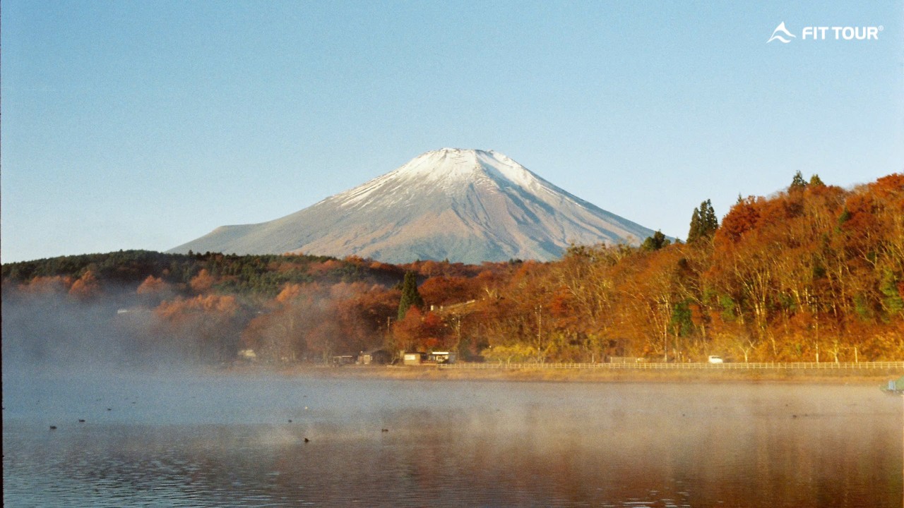 Núi Phú Sĩ hùng vĩ in bóng xuống mặt hồ mờ sương giữa khung cảnh rừng thu lá đỏ rực rỡ.